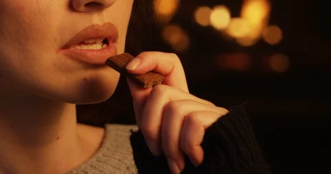 Bitting Chocolate Bar a Close Up of Pretty Girl Eating Dessert at Fireplace Stock Footage 103323573