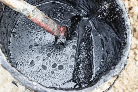 Bituminous mastic for waterproofing in a bucket. Application of bituminous Stock Photos