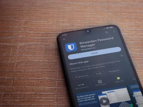 Bitwarden Password Manager app play store page on smartphone on wooden back.. Stock Photos