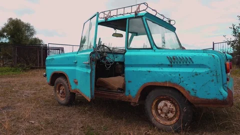 A bizarre old retro aqua-colored car on a meadow with one door opened. Stock Footage 114326046