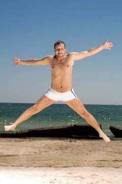 Bizarre young man jumping on a beach Stock Photos
