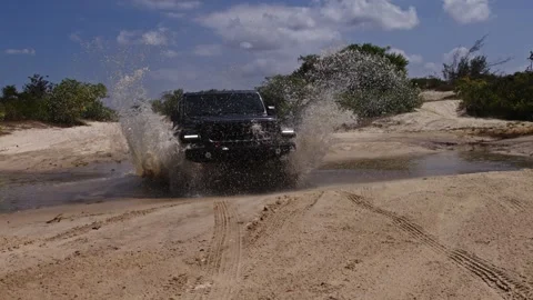 Black 4x4 SUV splashing through dune lagoon in Cumbuco Ceará Brazil slow motion Stock Footage 335151914