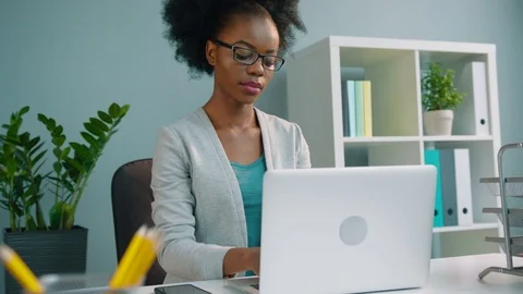 Black african american business woman in glasses working with laptop computer at Stock Footage