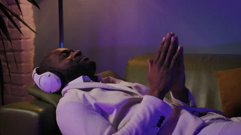 Black African American Guy lying on the Sofa Listen Music at Home Sings And Have Stock Footage 231556502