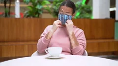 Young man with vitiligo having a cup of coffee in a cafeteria