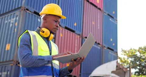 Black African engineer using laptop control checking container at cargo Stock Photos