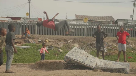 Black African kids jumping on mattress in Khayalitsha township. Stock Footage