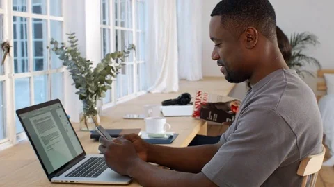 Black african man types message on phone in start up office Stock Footage 77509429