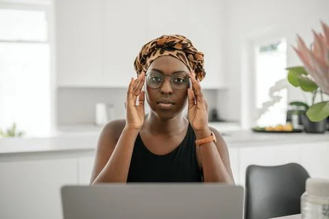 Black African woman working from home, wearing glasses and head scarf Stock Photos