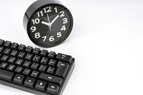 Black alarm clock beside computer keyboard symbolizing time management concept Stock-Fotos