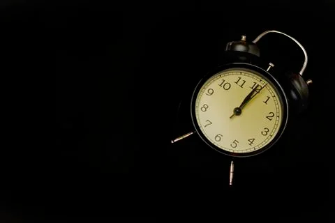 Black alarm clock with black background. Stock Photos