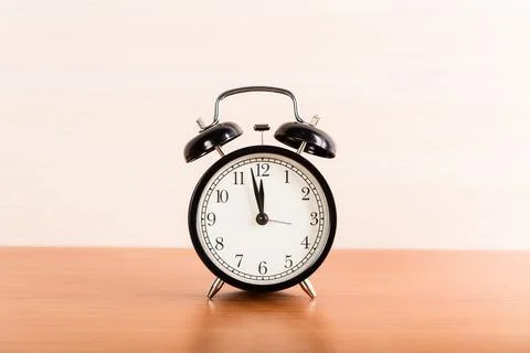 Black alarm clock on the table. Twelve oclock Stockfoto's