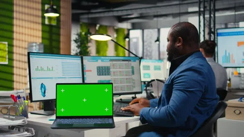 Black analyst uses computer to analyze charts with chroma key on laptop Stock Footage 313963146