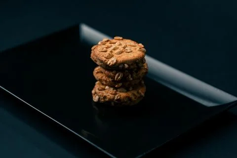 On black and blue background flat black plate with cookie cookies built in a Stock Photos