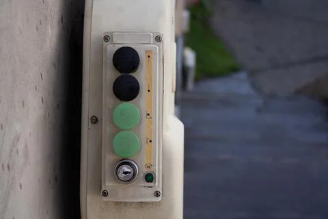 Black and green plastic button on a white elevator control panel Foto stock