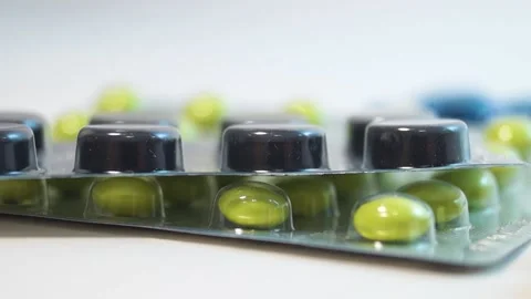Black and green tablets in blisters on a white background, close-up Stock Footage 171055417