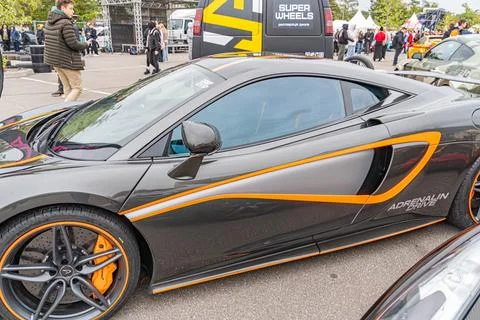 A black and orange high-performance Aston Martin is parked on a street during Foto stock