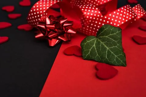 Black and red background with a red ribbon, a sprig of ivy and hearts Stock Photos