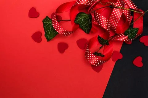Black and red background with a red ribbon, a sprig of ivy and hearts Foto stock