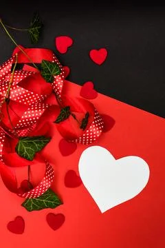 Black and red background with a red ribbon, a sprig of ivy and hearts Foto stock