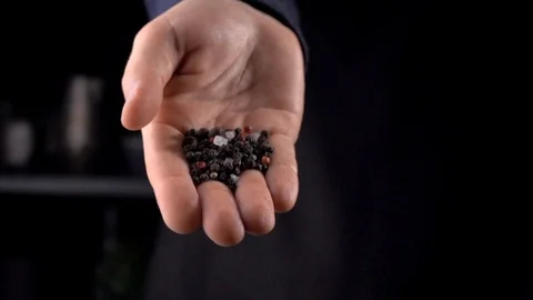Black and red pepper falling from man's hand on dark background 스톡 동영상 116337401