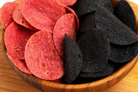 Black and red spicy chips in a wooden plate. Isolate. Stock Photos