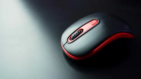 Black and red wireless computer mouse on a dark desk with strong copy space and 스톡 동영상 329480055