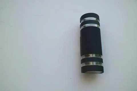 Black and silver flashlight lying on white surface Stock Photos