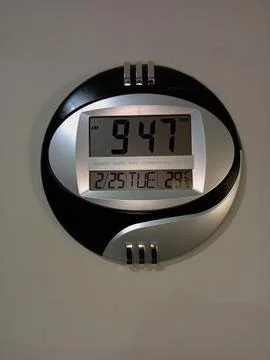 Black and silver round digital clock displaying time. Stock Photos