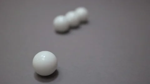 Black and white balls rolling around and colliding randomly on the gray suface Stock Footage 147105925