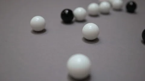 Black and white balls rolling around and colliding randomly on the gray suface Stock Footage 147107309