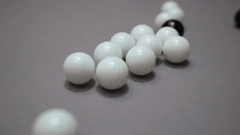 Black and white balls rolling around and colliding randomly on the gray suface Stock Footage 147108011