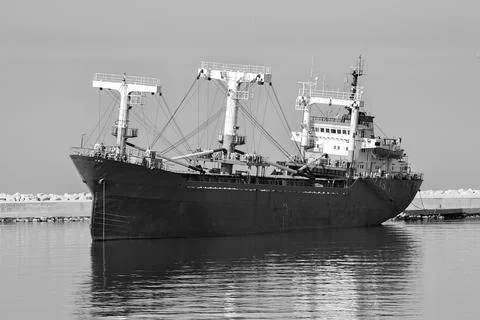 Black and White Cargo Ship Docked at Port with Breakwater Stock Photos