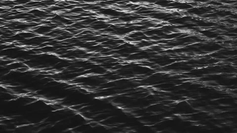Black and white close-up of ocean water surface with gentle ripples and light Stock Footage 311488256