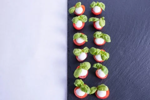 Black and white composition of basil, tomatoes, mozzarella on a stone black t Stock Photos