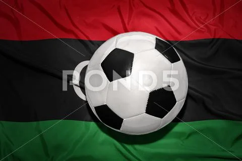 Black and white football ball on the national flag of libya Stock Photos