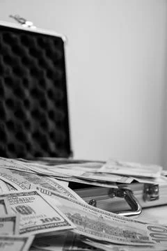 A black and white image of an open metal briefcase with stacks of cash spil.. Stock Photos