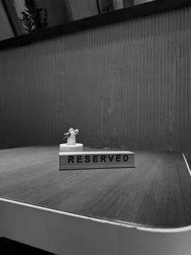 Black and white image of reserved sign on empty table, evoking feelings of .. Stock Photos