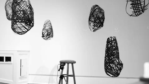 Black and white interview setup in a room of hanging art sculptures slowly Video stock 96620417