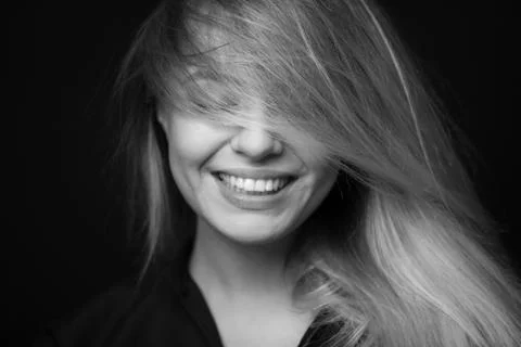 Black and white portrait of a beautiful smiling woman on a dark background Stock Photos