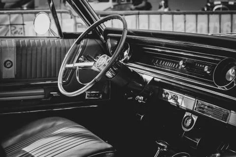 A black and white portrait of the interior of an oldtimer car. The steering w Stock Photos