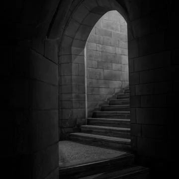 Black and white square perspective looking through a dark stone arch toward a Stock Photos