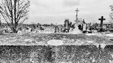 Black and white static close-up of a rustic stone wall with a cemetery cross in  Vídeos de archivo 332804026