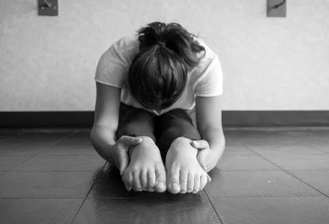 Black and white version of Young woman performing and sit and reach to stretch Stock Photos