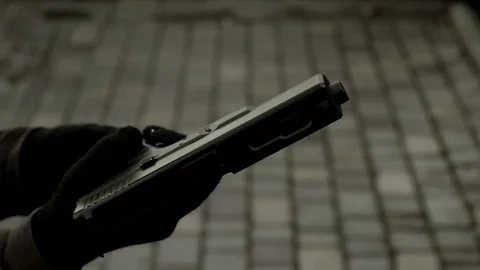 Black and white video hands of a man in gloves with a weapon or pistol reloading Stock Footage 253895310