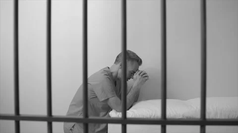 Black and white view of scene of a prayerful inmate in prison Stock Footage 60574398
