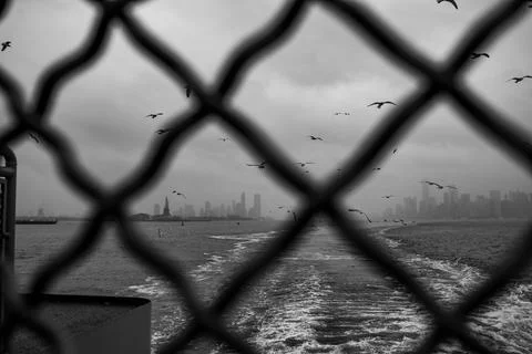 A black and white view of the Statue of Liberty and Manhattan skyline seen .. Stock Photos