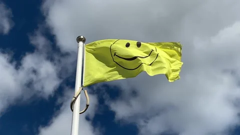 Black and yellow smiley flag blowing in wind Stock Footage
