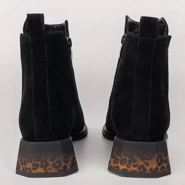 Black ankle boots with leopard print heels stand on a plain background show.. Stock Photos