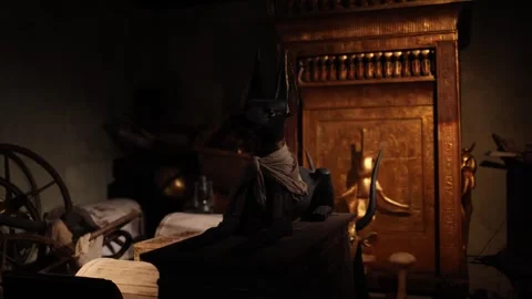 A black Anubis statue resting atop a wooden chest in a dimly lit tomb chamber. T Stock Footage 301792045